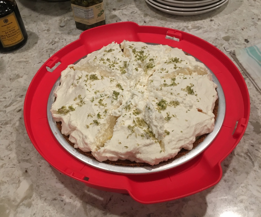 A whole lime pie in its pie tin. It is topped with whipped cream and lime zest.